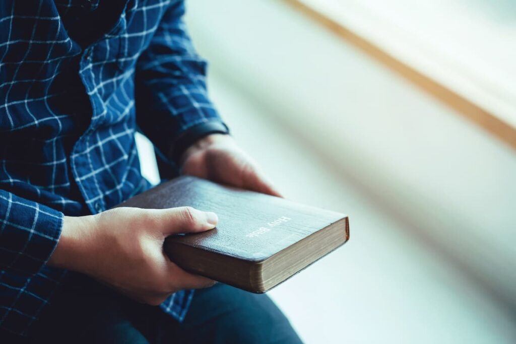 Man sitting while holding Bible