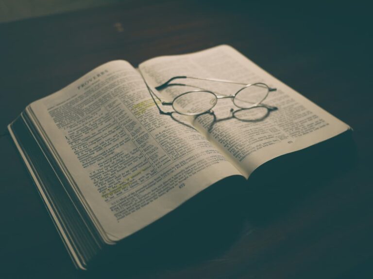 Open Bible with eyeglasses resting on the pages, representing study, preaching, and pastoral ministry in the church.