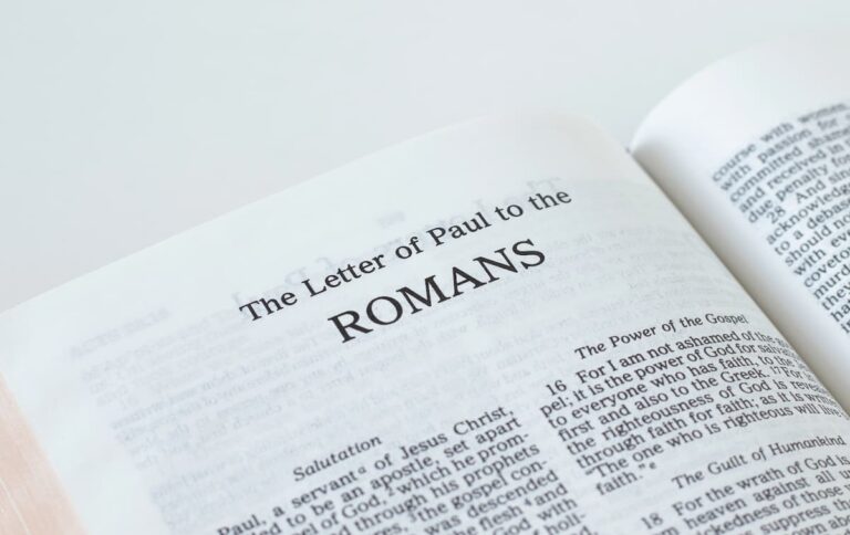 Open Bible on a soft white surface showing the opening page of the Letter of Paul to the Romans and the Power of the Gospel heading.