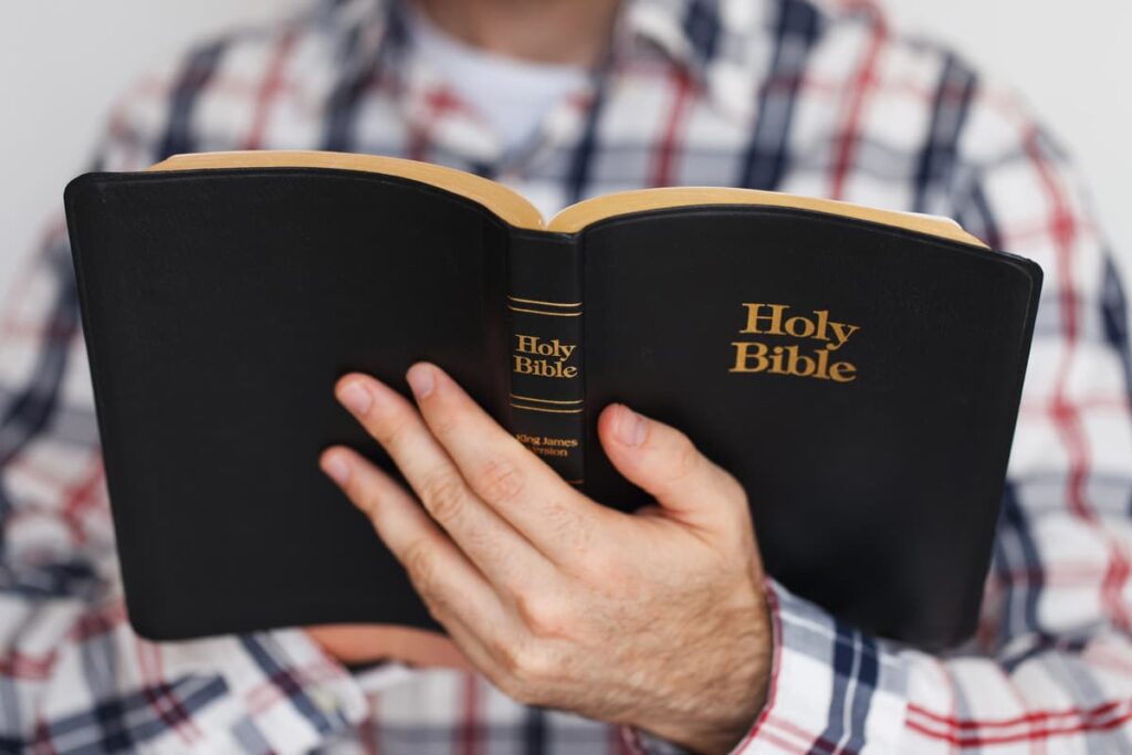 Man Holding and Reading an Open King James Version Holy Bible